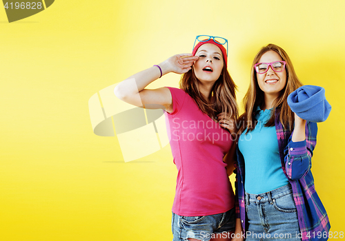Image of lifestyle people concept: two pretty young school teenage girls having fun happy smiling on yellow background 