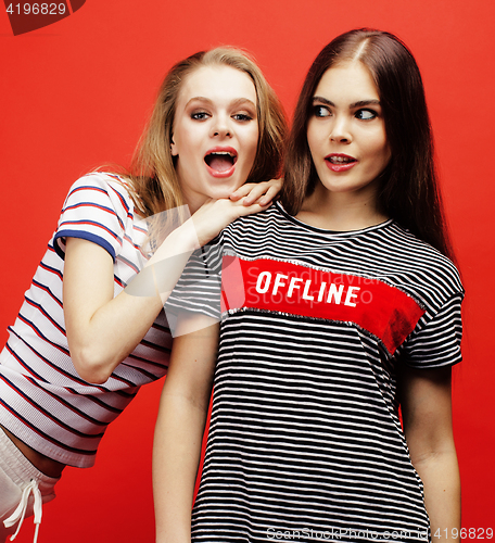 Image of two best friends teenage girls together having fun, posing emotional on red background, besties happy smiling, lifestyle people concept close up