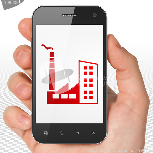 Image of Industry concept: Hand Holding Smartphone with Industry Building on display