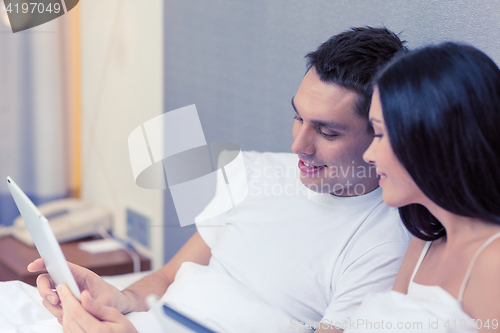 Image of smiling couple in bed with tablet pc computers