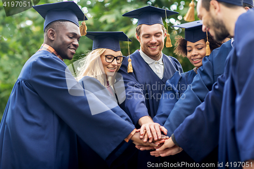 Image of happy students in mortar boards with hands on top