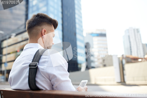 Image of close up of man texting on smartphone in city