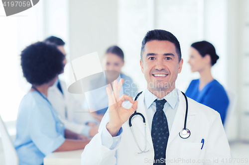 Image of happy doctor over group of medics at hospital