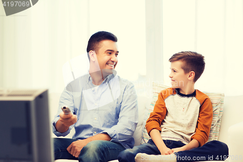 Image of smiling father and son watching tv at home