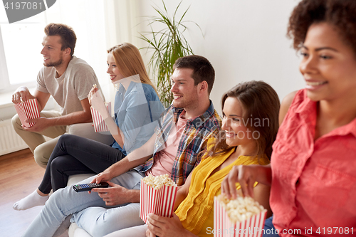 Image of happy friends with popcorn watching tv at home