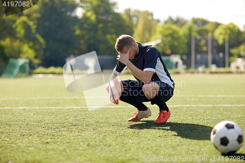 Image of sad soccer player with ball on football field