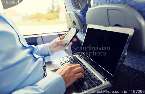 Image of man with smartphone and laptop in travel bus