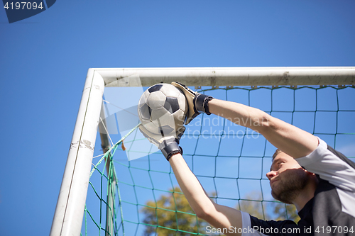 Image of goalkeeper with ball at football goal on field