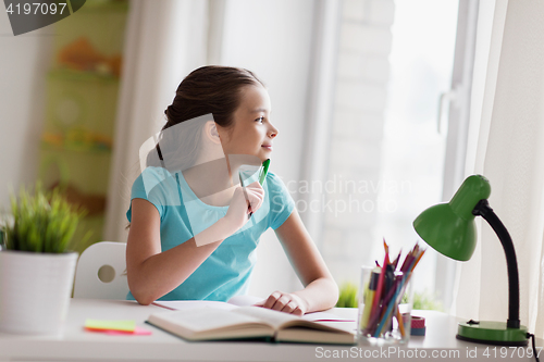 Image of happy girl with book writing to notebook at home