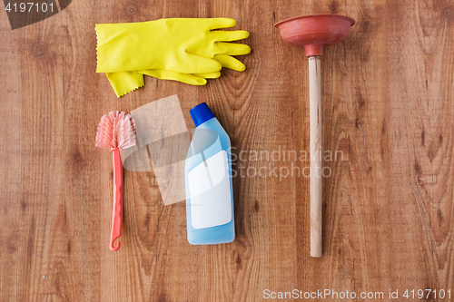 Image of plunger with cleaning stuff on wooden background