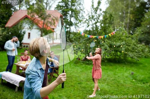 Image of happy friends playing badminton at summer garden