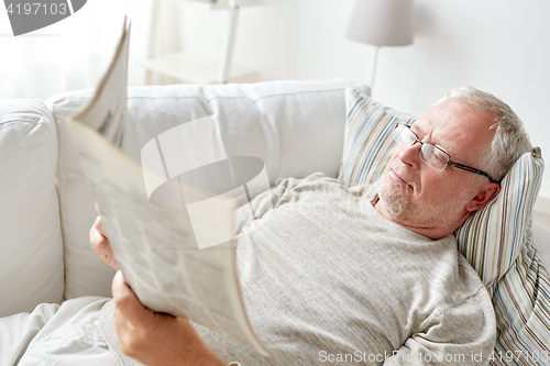 Image of close up of senior man reading newspaper at home