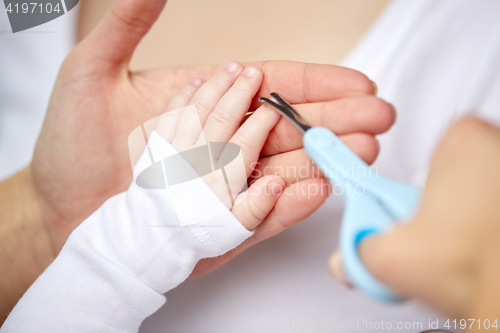 Image of close up of hand with scissors trimming baby nails