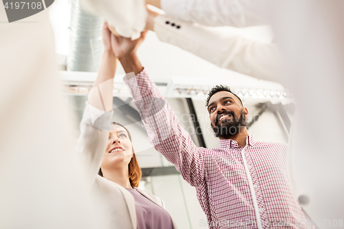 Image of happy business team making high five at office