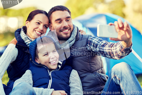 Image of family with smartphone taking selfie at campsite