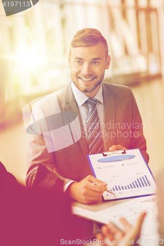 Image of smiling businessman with graph at business meeting