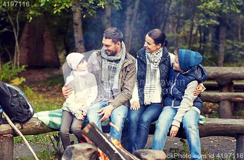 Image of happy family sitting on bench at camp fire