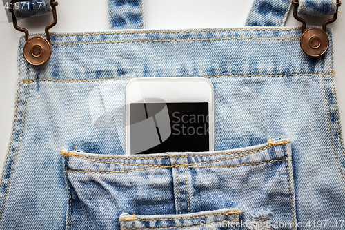 Image of smartphone in pocket of denim overalls