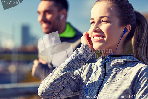 Image of happy couple with earphones running in city