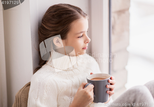 Image of girl with cacao mug sitting at home window