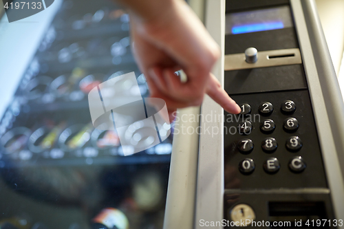 Image of hand pushing button on vending machine keyboard