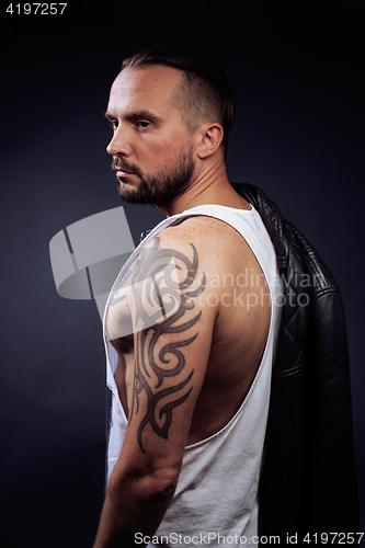 Image of A man with tattooes on his arms. Silhouette of muscular body. caucasian brutal hipster guy with modern haircut, looking like criminal