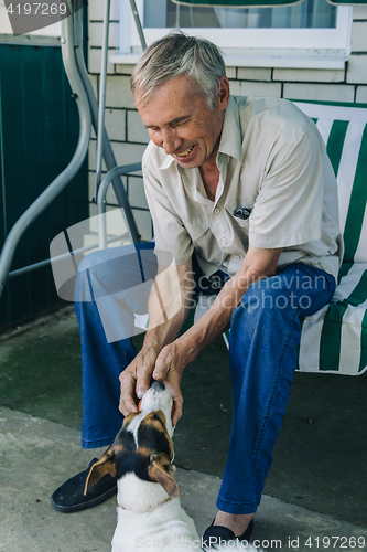 Image of Senior man playing with dog