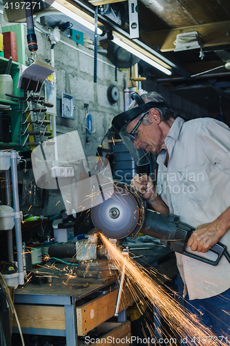 Image of Senior man working with angle grinder