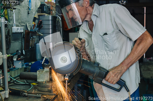 Image of Senior man working with angle grinder