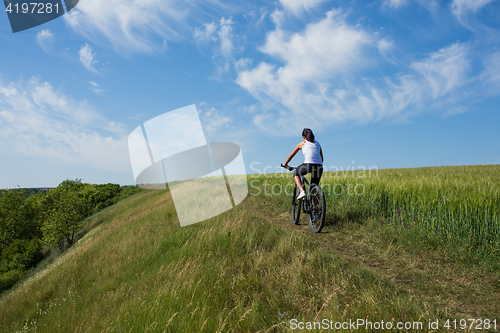 Image of woman going for bike ride on sunny day in countryside