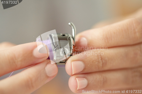 Image of tailor hands with spool of sewing machine