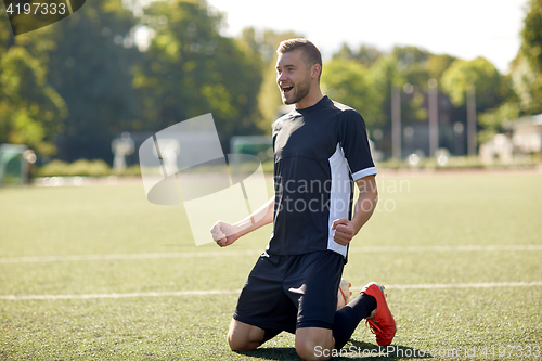 Image of happy soccer player with ball on football field