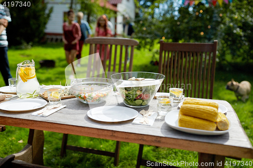 Image of people coming to table with food at summer garden