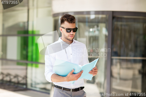 Image of young man with business file on city street