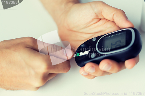 Image of close up of man checking blood sugar by glucometer