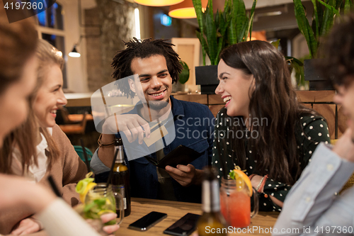 Image of friends with drinks, credit card and bill at bar