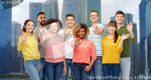 Image of international group of happy people waving hand