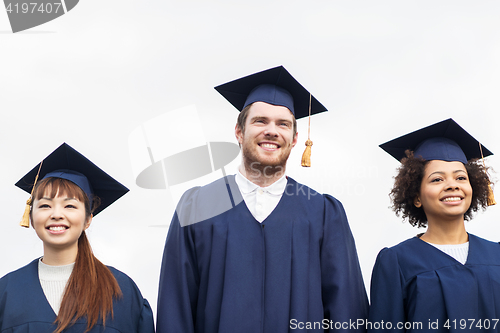 Image of happy students or bachelors in mortar boards