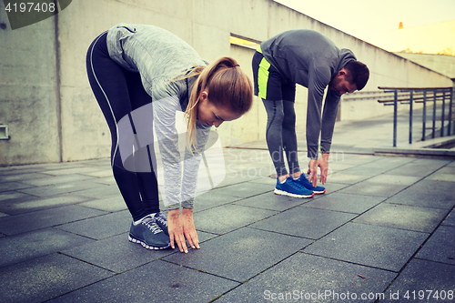 Image of couple stretching and bending forward on street