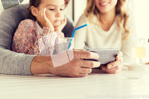 Image of close up of family with smartphone at restaurant