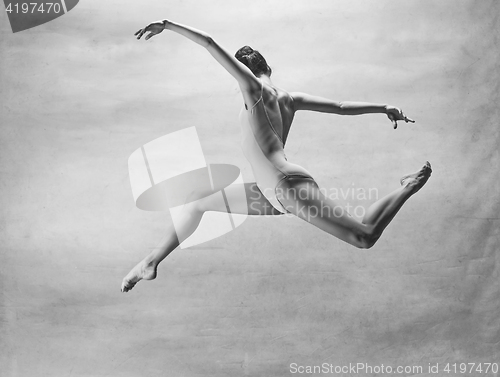 Image of Young beautiful modern style dancer jumping on a studio background