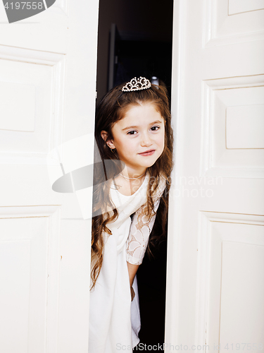 Image of little cute girl at home, opening door well-dressed in white dre