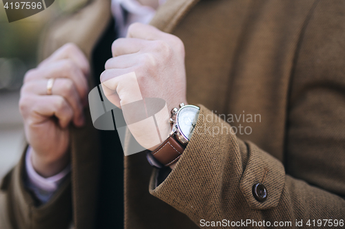 Image of Men watches on hand in coat