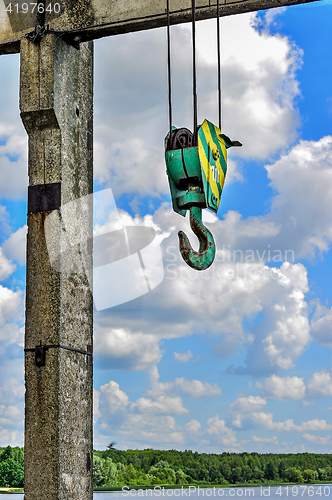 Image of Yellow-green hook of a construction crane on a rope on a background of clouds