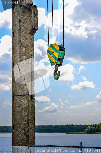 Image of Yellow-green hook of a construction crane on a rope on a background of clouds