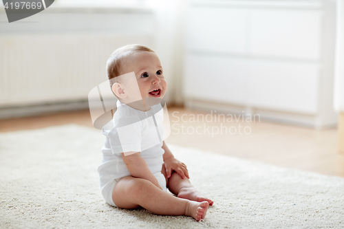 Image of happy baby boy or girl sitting on floor at home