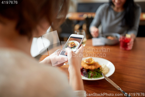 Image of women with smartphones and food at restaurant