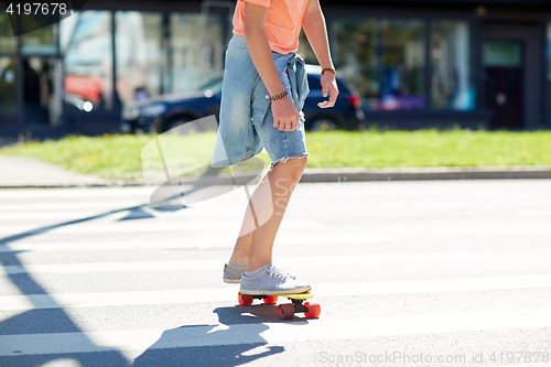 Image of teenage boy on skateboard crossing city crosswalk