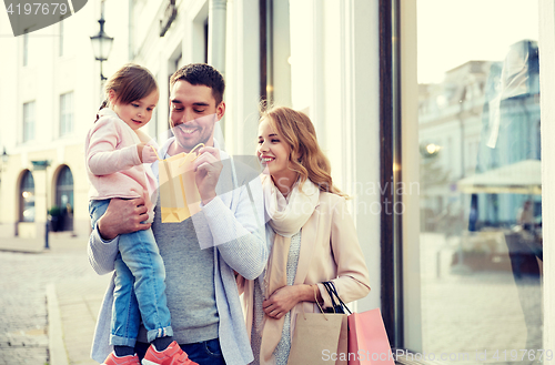 Image of happy family with child and shopping bags in city