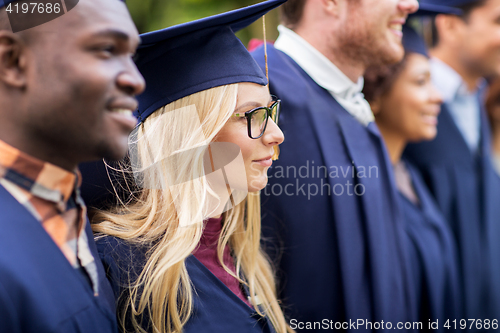 Image of happy students or bachelors in mortar boards